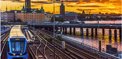 Trem chegando a Stockholm ao entardecer, com a silhueta da cidade ao fundo